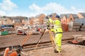 Site engineer in hi-viz installing surveying instrument on construction site