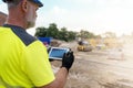 Site engineer surveyor using rugged tablet controller computer to operate EDM total station for setting out and surveying