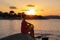 Sithonia - Silhouette of sitting tourist woman relaxing with scenic view of sunset over Aegean Mediterranean Sea on Karydi beach Royalty Free Stock Photo
