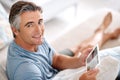 Sitting back and relaxing. Cropped portrait of a handsome mature man using a tablet while sitting on his living room Royalty Free Stock Photo