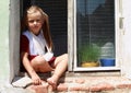 Sitting barefeet girl in a window with broken hand