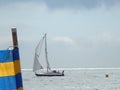 Sailing boat travels past the beach, with wind breaker in view