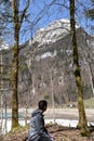 A sitting boy between conifer trees observing KlÃÂ¶ntalersee lake in early spring sunny day in KlÃÂ¶ntal Royalty Free Stock Photo