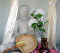 Sitting Buddha with a Fan, Flowers, and a Vase in front.