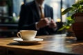 Sitting businessman with aromatic coffee on a wooden table, saucer