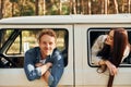 Sitting in the car. Young couple is traveling in the forest at daytime together Royalty Free Stock Photo