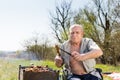 Sitting Elderly Man Holding Grilled Meat and Knife