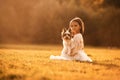 Sitting on the grass. Cute little girl is on the field with dog Royalty Free Stock Photo