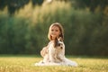 Sitting on the grass. Cute little girl is on the field with dog Royalty Free Stock Photo