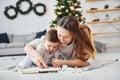 Sitting on the ground. Mother with her little daughter is indoors at home together Royalty Free Stock Photo