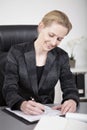 Sitting Happy Businesswoman Writing at her Desk Royalty Free Stock Photo