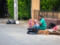 Sitting Homeless Man Sorting Out Junk in Black Plastic Bag