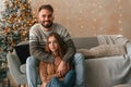 Sitting and looking forward. Lovely young couple are celebrating New Year at home