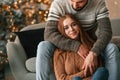 Sitting and looking forward. Lovely young couple are celebrating New Year at home