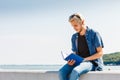 Sitting man reading book outside on sunny day