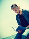 Sitting man reading book outside on sunny day Royalty Free Stock Photo