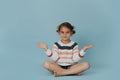 Sitting in meditation easy pose little girl in striped sweater