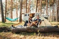 Sitting near the tent. Young couple is traveling in the forest at daytime together Royalty Free Stock Photo