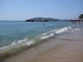 Sitting places, people and palm trees at sandy beach on bay of ACAPULCO city in Mexico with white waves of Pacific Ocean Royalty Free Stock Photo