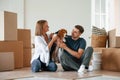 Sitting and playing with dog. Young couple are moving to new home Royalty Free Stock Photo