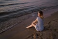 Sitting: Portrait of a Beautiful blonde woman in a light blue dress on the Baltic Sea beach during sunset with vivid Royalty Free Stock Photo