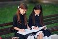 Sitting and reading. Two schoolgirls is outside together near school building Royalty Free Stock Photo