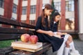 Sitting and reading. Two schoolgirls is outside together near school building Royalty Free Stock Photo