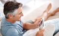 Sitting and relaxing on the couch. a handsome mature man using a tablet while sitting on his living room sofa. Royalty Free Stock Photo