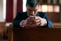 Sitting in silent prayer. Shot of a young man praying in a church. Royalty Free Stock Photo