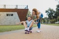 Excited funny girl sitting on skateboard near her mother