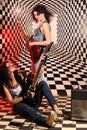 Sitting and standing women play electric guitar in studio Royalty Free Stock Photo