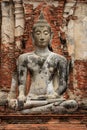 Sitting stone Buddha with red brick in the back in Ayutthaya Historical Park, Thailand