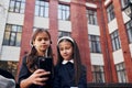 Sitting together. Two schoolgirls is outside near school building Royalty Free Stock Photo