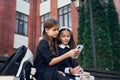 Sitting together. Two schoolgirls is outside near school building Royalty Free Stock Photo