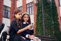 Sitting together. Two schoolgirls is outside near school building Royalty Free Stock Photo