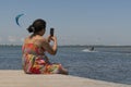 Sitting woman on a pontoon bridge with a kite surfer