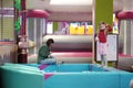 Sitting woman and standing child on soft equipment inside the Lider indoor playground.