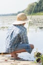 Sitting on wooden bridge shoeless fisherman with