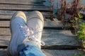 Close up of teenager`s feet in modern and trendy white sneakers and rolled up jeans. Sunny summer day. Royalty Free Stock Photo