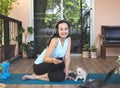 Sitting  on yoga mat in balcony  with computer laptop dumbbell and Chihuahua dog., smiling and looking at camera. Yoga training Royalty Free Stock Photo