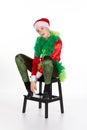Sitting young girl wearing red santa clause hat head cocked to side looking up coyly