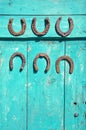 Six antique rusty horseshoe on green wooden farm barn door Royalty Free Stock Photo