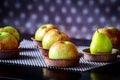 Six apples and one green pear on a brown table in paper plates Royalty Free Stock Photo