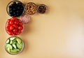 Six bowls with tomatoes, black olives, fresh cucumbers, colored peppers, pink salt and walnuts Royalty Free Stock Photo