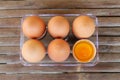 Six brown eggs in plastic box on bamboo table with one broken egg, top view Royalty Free Stock Photo