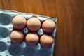 Six brown raw hen eggs on gray tray lying on wooden table Royalty Free Stock Photo