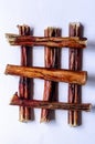 Six bully sticks. Dried bull pizzle regular for pets. Stacked perpendicular to each other. White background. Shooting from above.