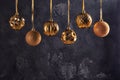 Six Christmas balls of golden color are hanging by a ribbon. Beautiful composition with copy space on black textured Royalty Free Stock Photo