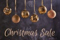 Six Christmas balls of golden color are hanging by a ribbon. Festive composition with the inscription Christmas Sale Royalty Free Stock Photo