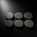 Six circular stone discs arranged in two rows on a dark, smooth surface Royalty Free Stock Photo